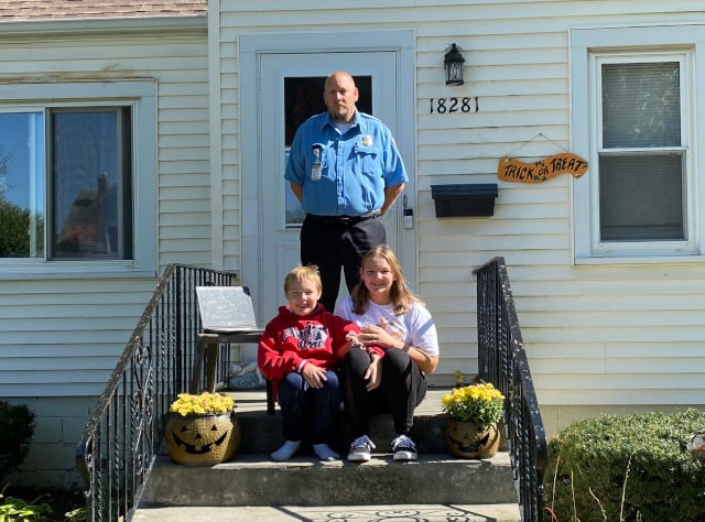 The Arnold family—Matt (standing), Mason (left), and Jasmine—waited on their porch for the procession to pass their house on Burnham Avenue. Mom Jen was at work and unable to join in showing her respects. (Photo: Melanie Jongsma)