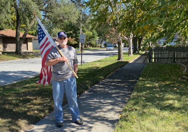 Lansing resident Norm Coyle awaited the procession, ready to raise a flag in respect. (Photo: Melanie Jongsma)