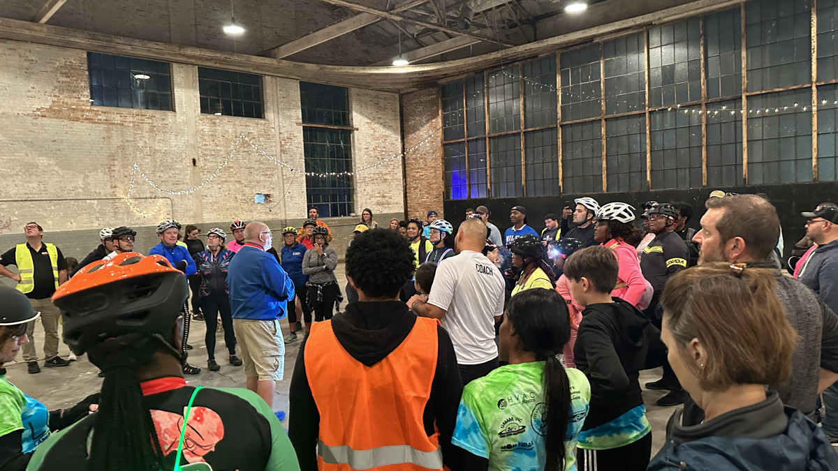 Director of Venue Operations Ken Reynolds (blue shirt, khaki shorts) greeted the bikers and explained the Village of Lansing's plans for using the Ford Hangar as an event venue. (Photo: Melanie Jongsma)